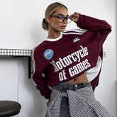 Woman wearing a maroon and white sweatshirt with text and graphics, standing indoors.